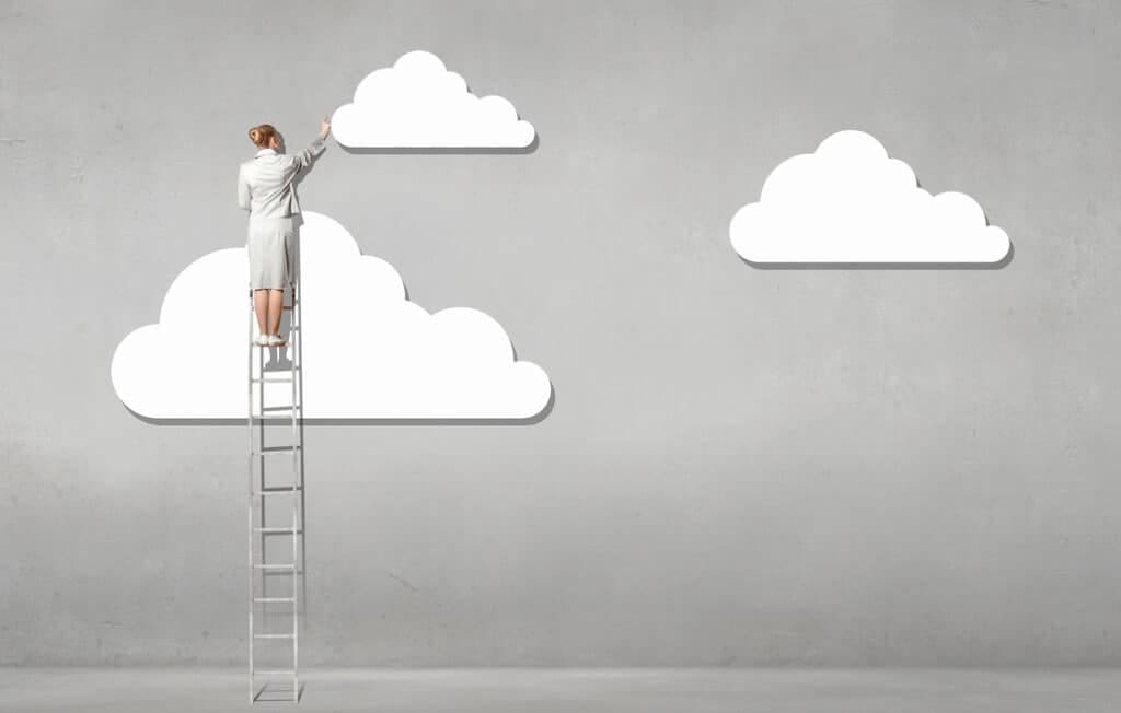 Woman on a ladder reaching for paper clouds
